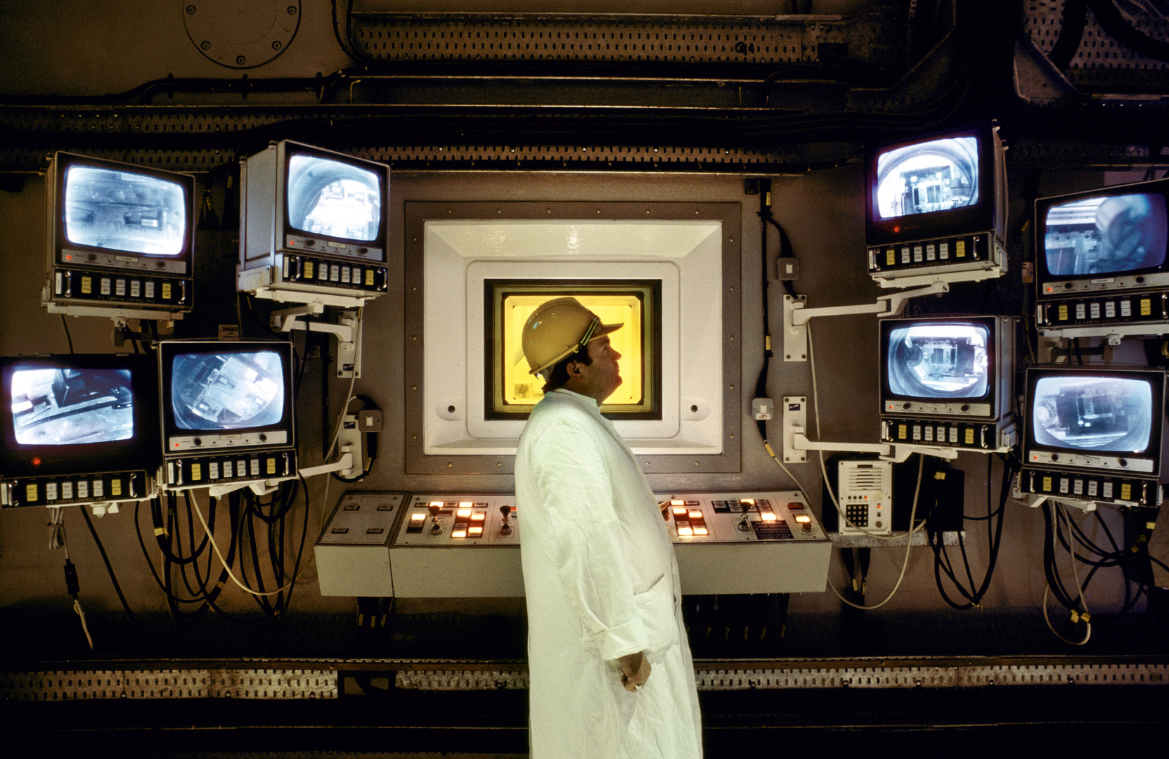 Worker in a white lab coat monitoring screens in the control room of the Sellafield nuclear plant.