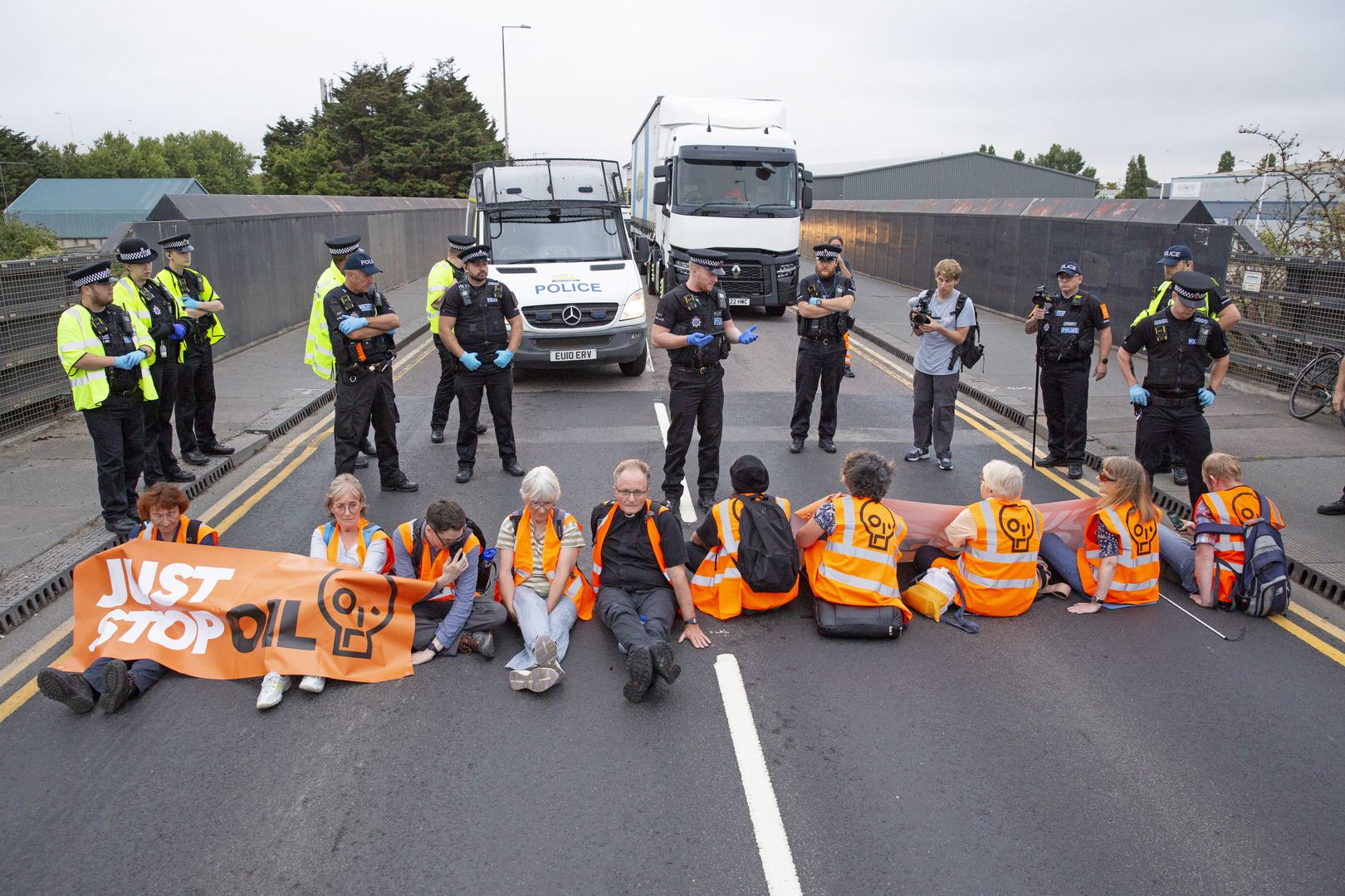 Just Stop Oil protestors glued to the road, police officers present.