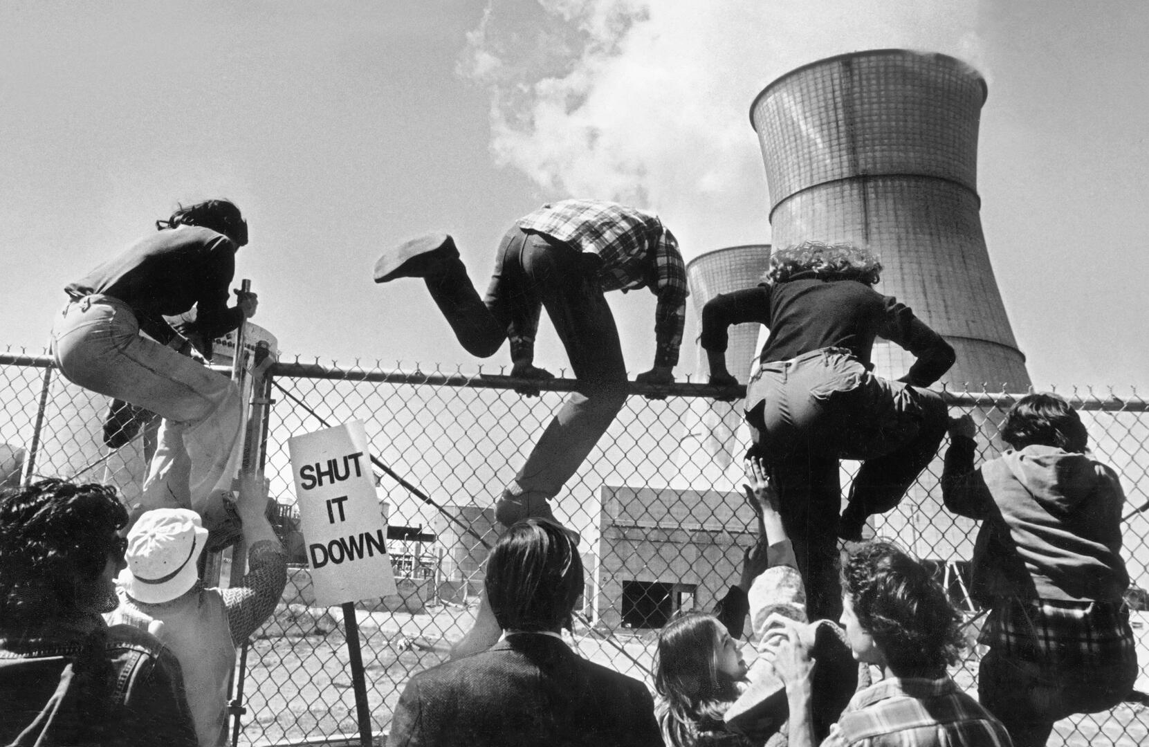 Protestors climbing a fence at Rancho Seco nuclear power plant, holding a 